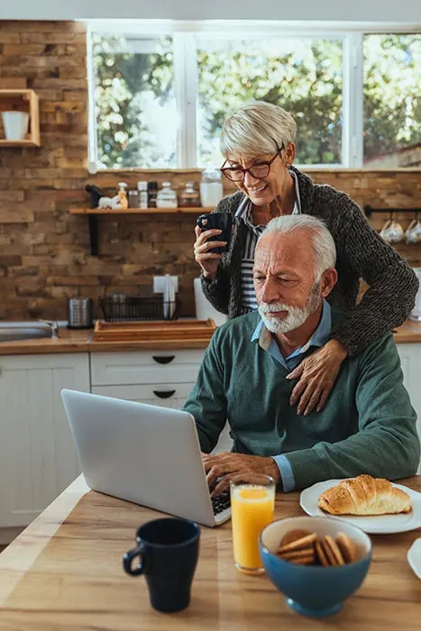 senior couple at their dining table working on a laptop computer