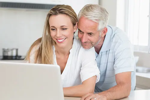 couple sitting on couch using laptop